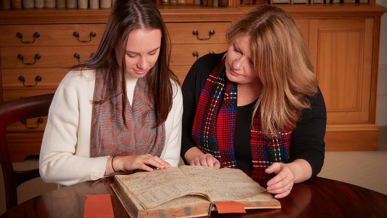 Sophie George and Johnstons of Elgin Chairwoman Jenny Urquhart looking at an archive journal in our archive room